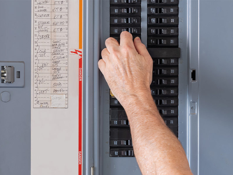 closeup of a hand manipulating a switch on an electrical panel