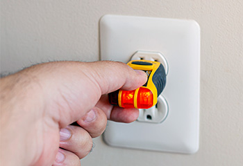 closeup of a hand plugging a voltage tester into a power outlet