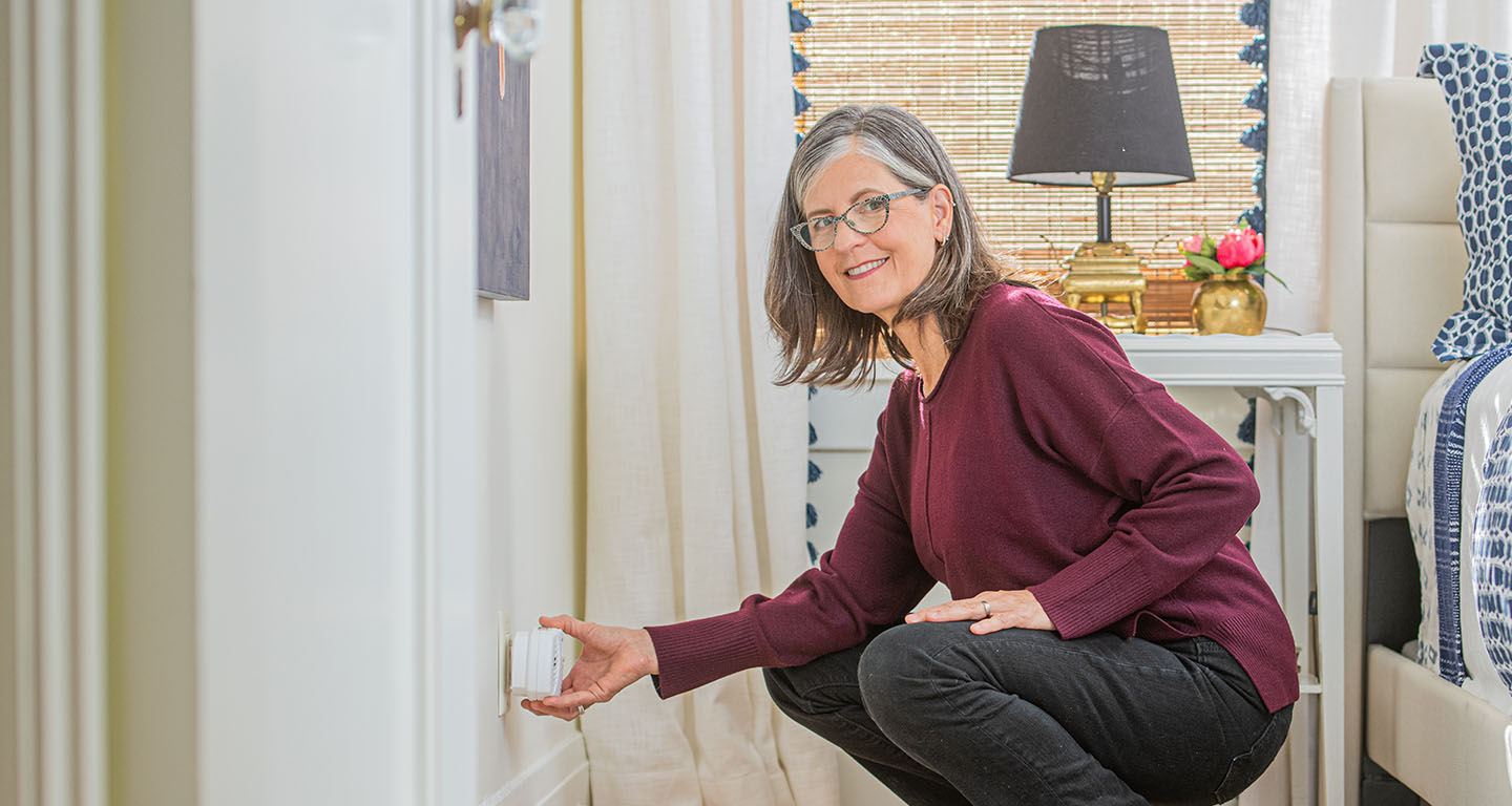 woman kneeling down to plug in a carbon monoxide detector