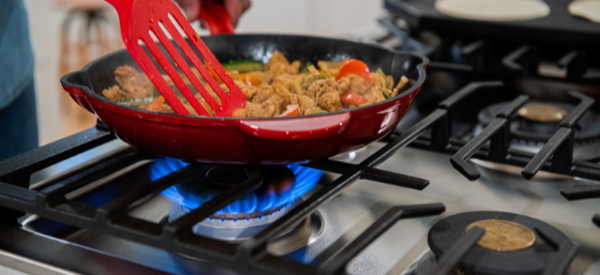 close up of food being cooked in a skillet on a gas stovetop