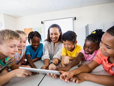 an adult woman and group of children sitting around a table looking at an envelope