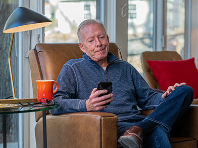 An older man looks at an incoming cell phone call with skepticism