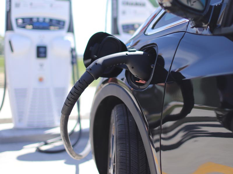 Close-up shot of electric vehicle plugged in at charging station